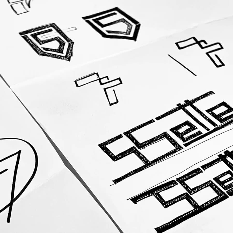 Esbossos a llapis de la S de Sette sobre paper, l'estudi dibuixant el logo a mà